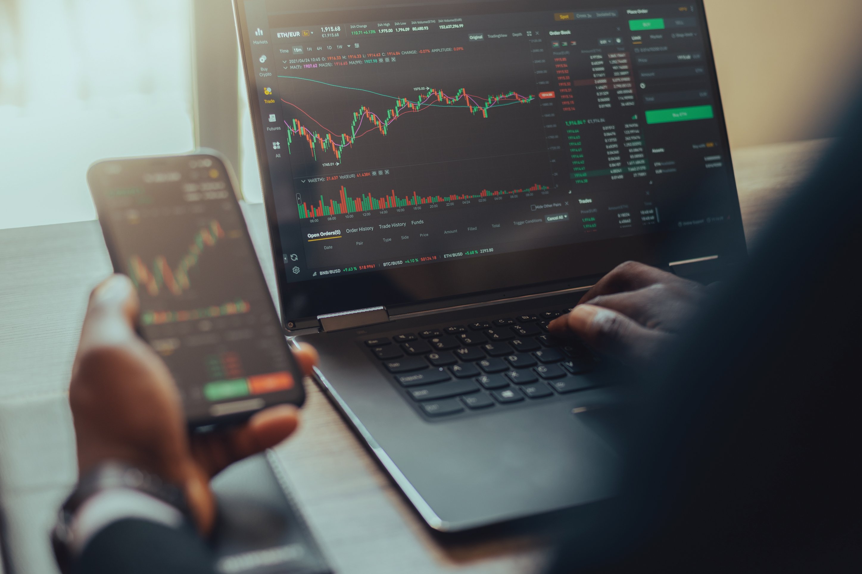Photo of someone tracking investments on a computer and phone.