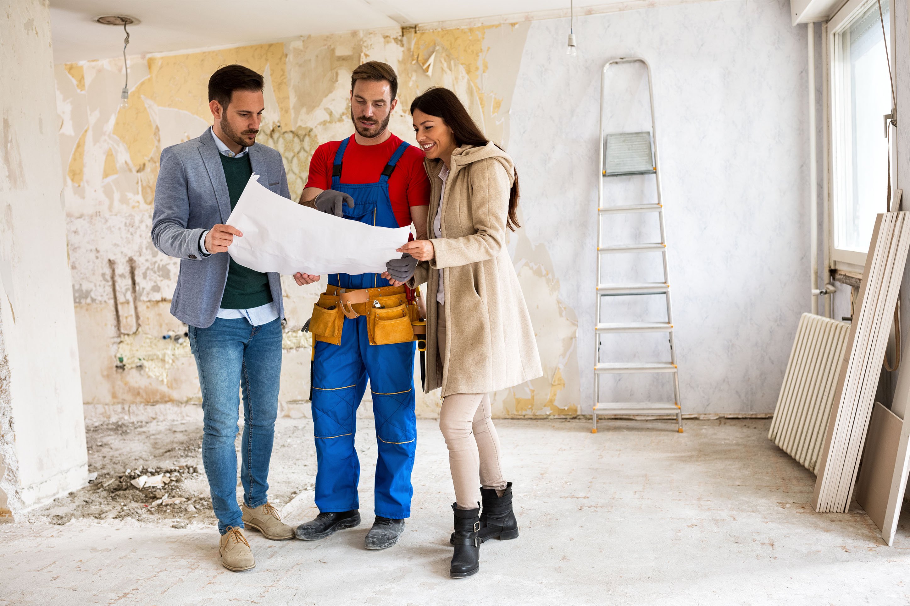 Couple looking at home rennovation plans with carpenter. 