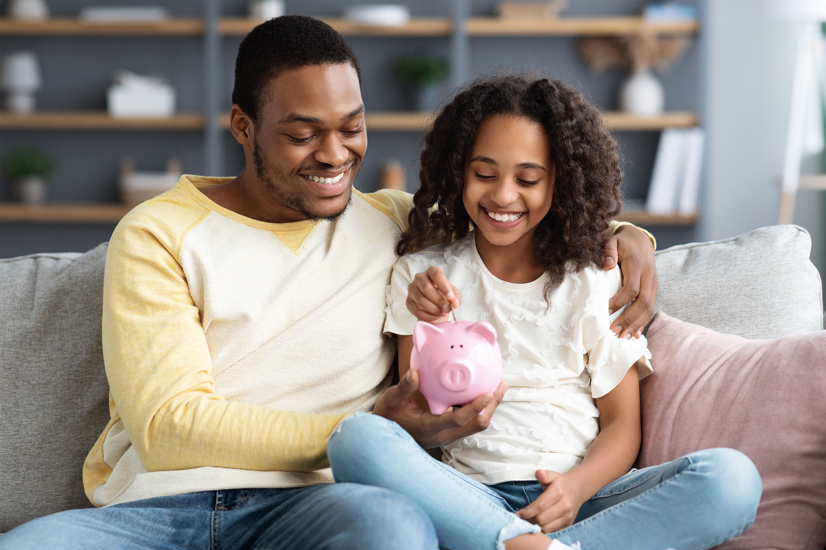 Father and daughter putting money into a piggy bank. 
