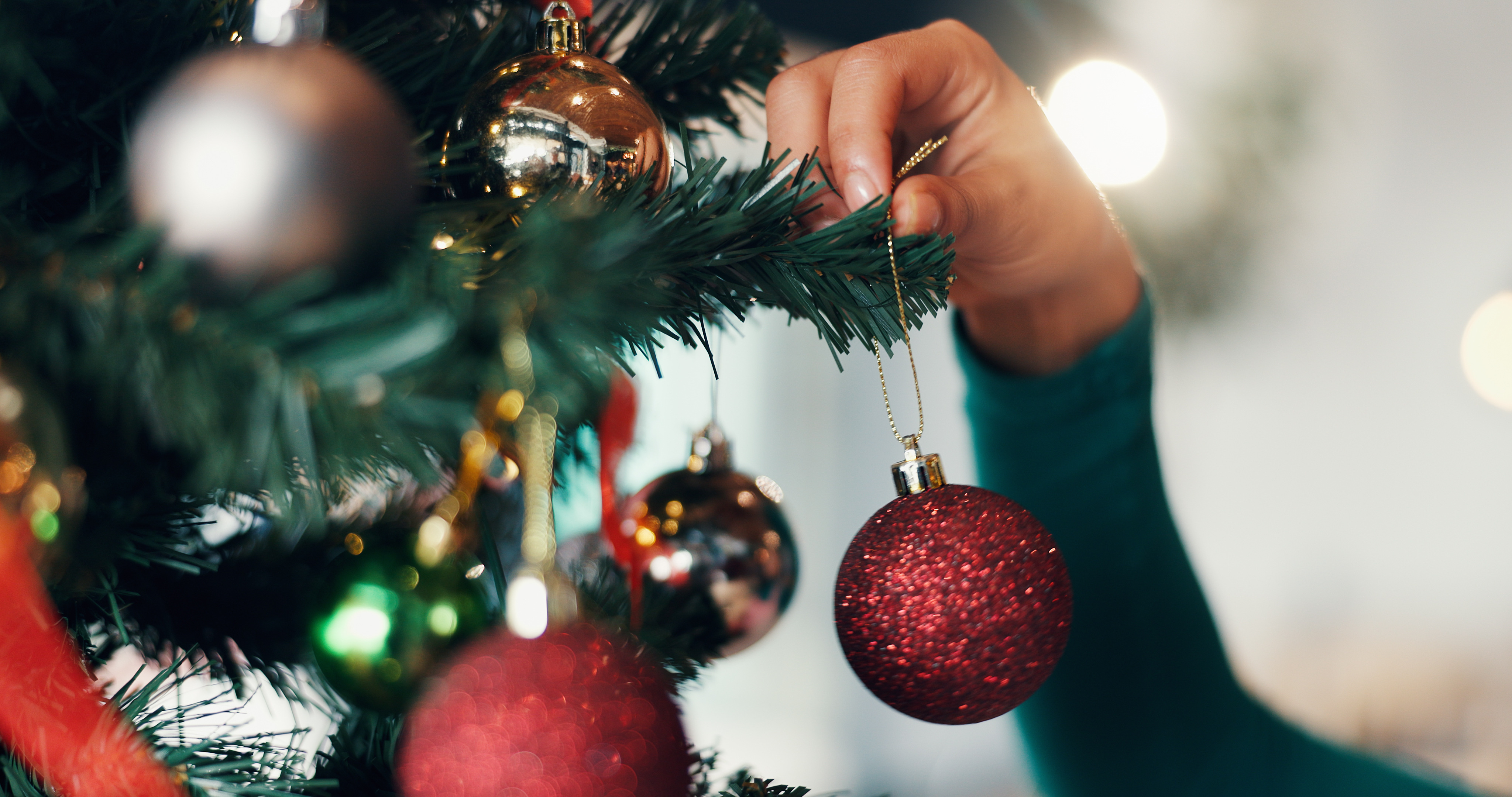Photo of a person putting ornaments on a Christmas tree