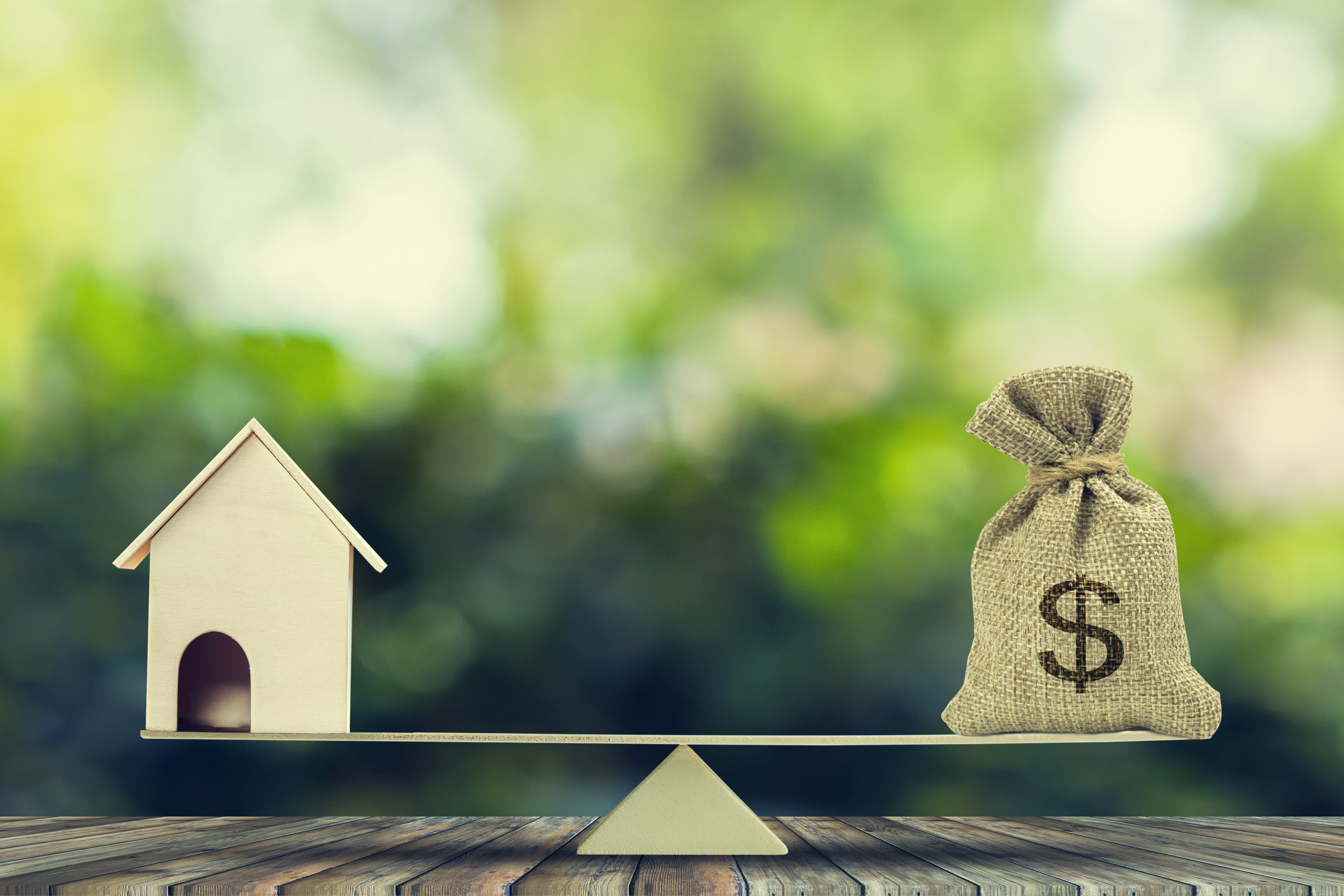 Image of a home and a bag of money on a scale