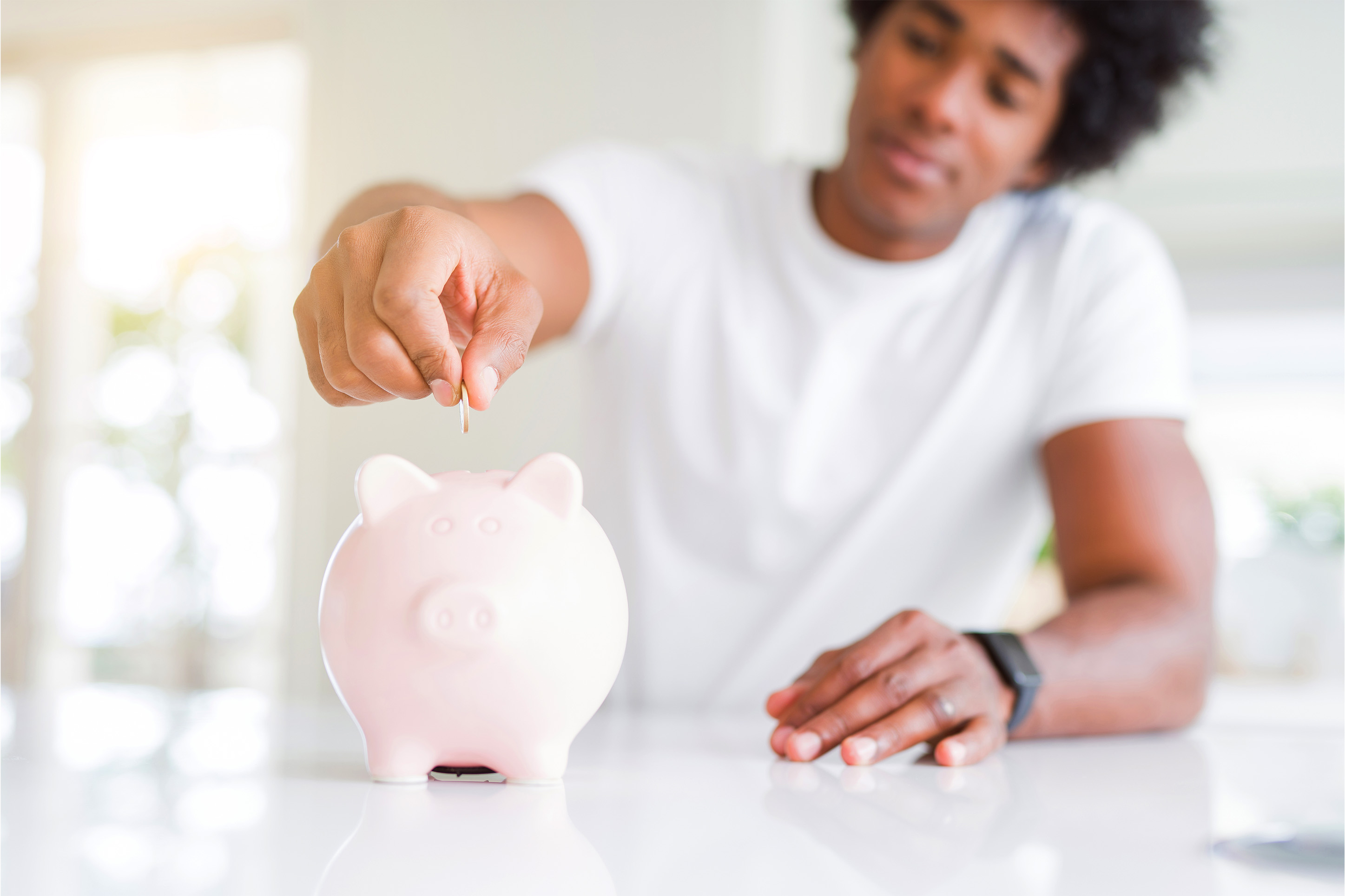 Man putting money in a piggy bank. 