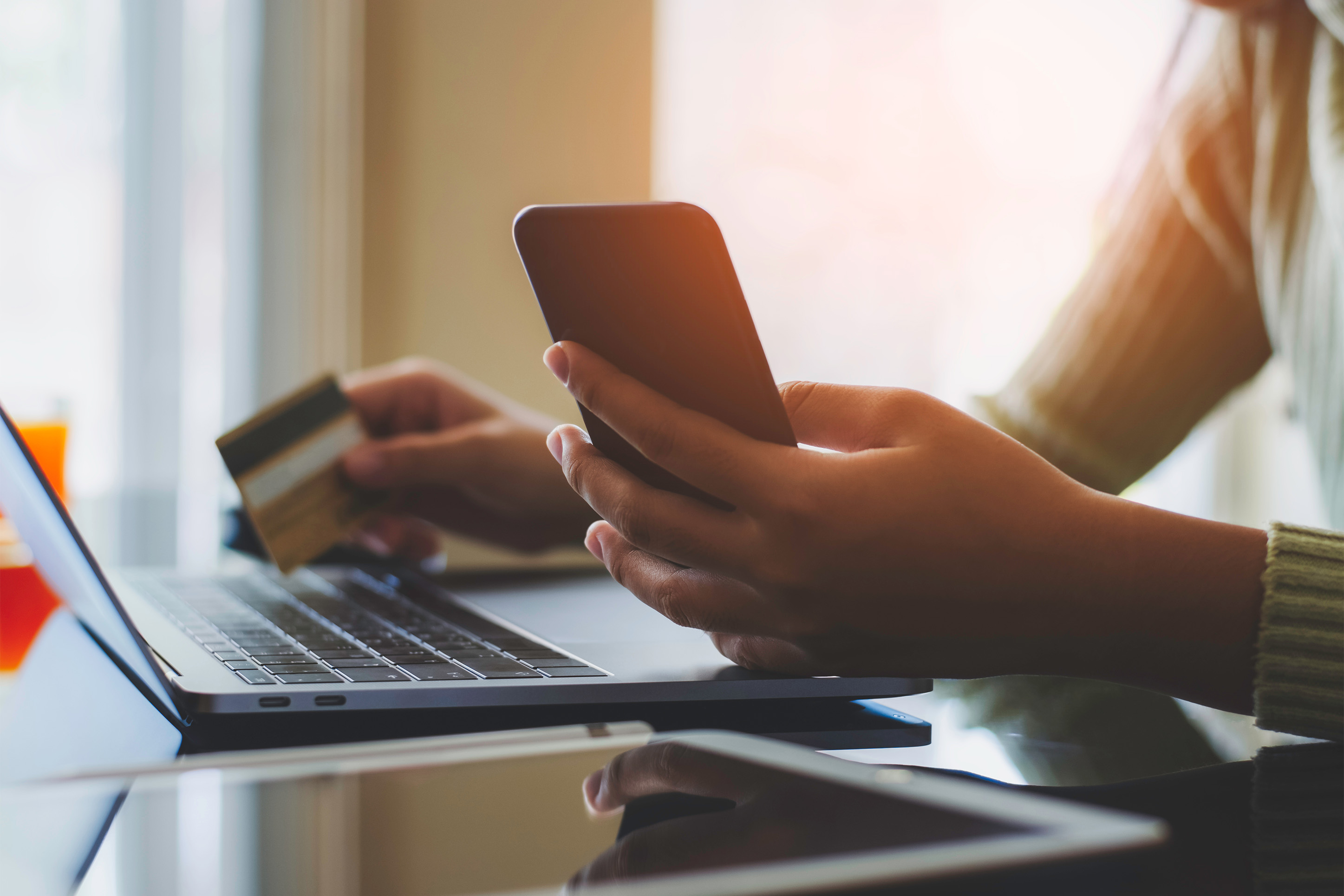Someone purchasing something online with a computer and phone. 