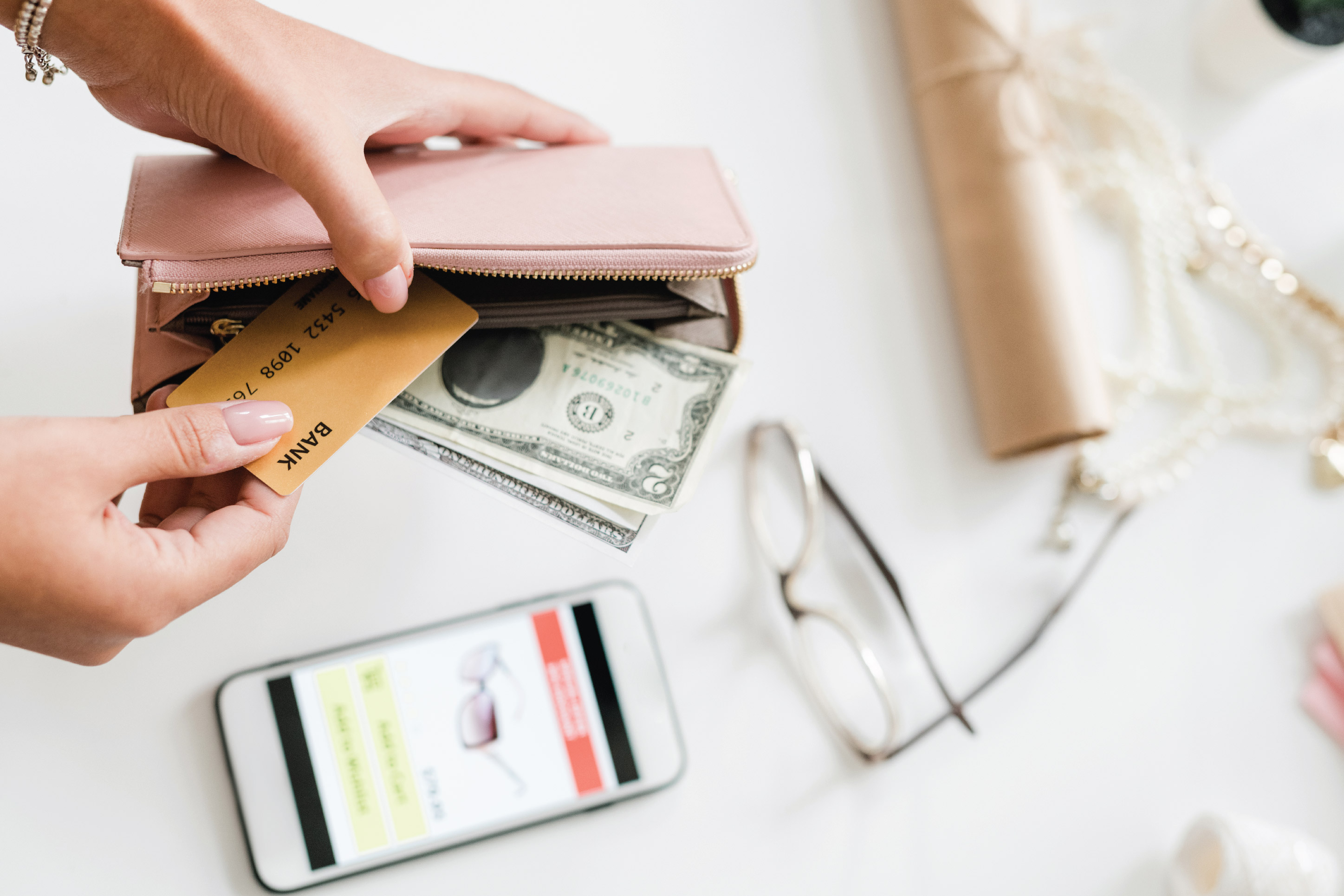 woman pulling a credit card and cash out of her wallet