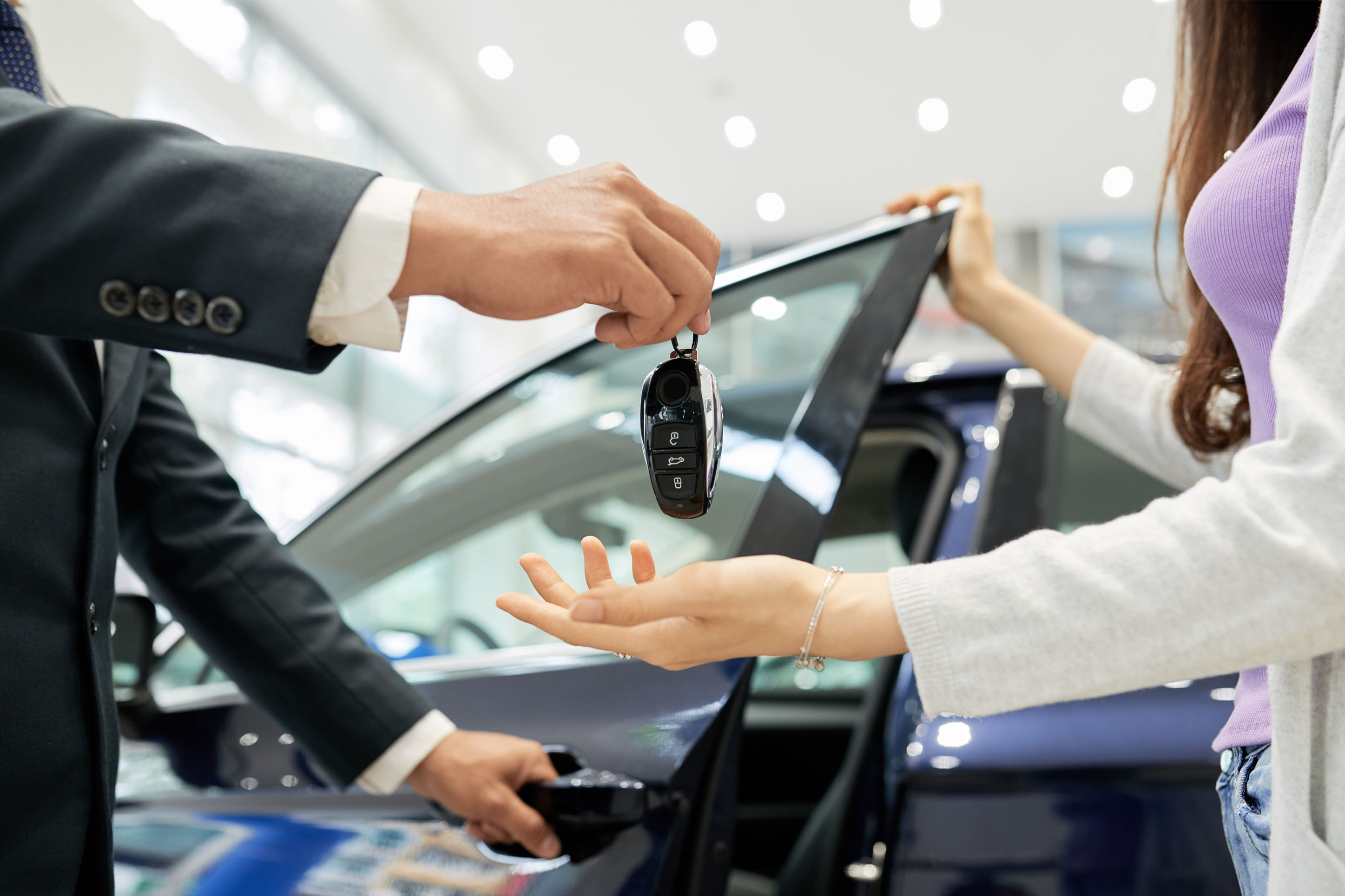 Image of someone getting keys to new car. 