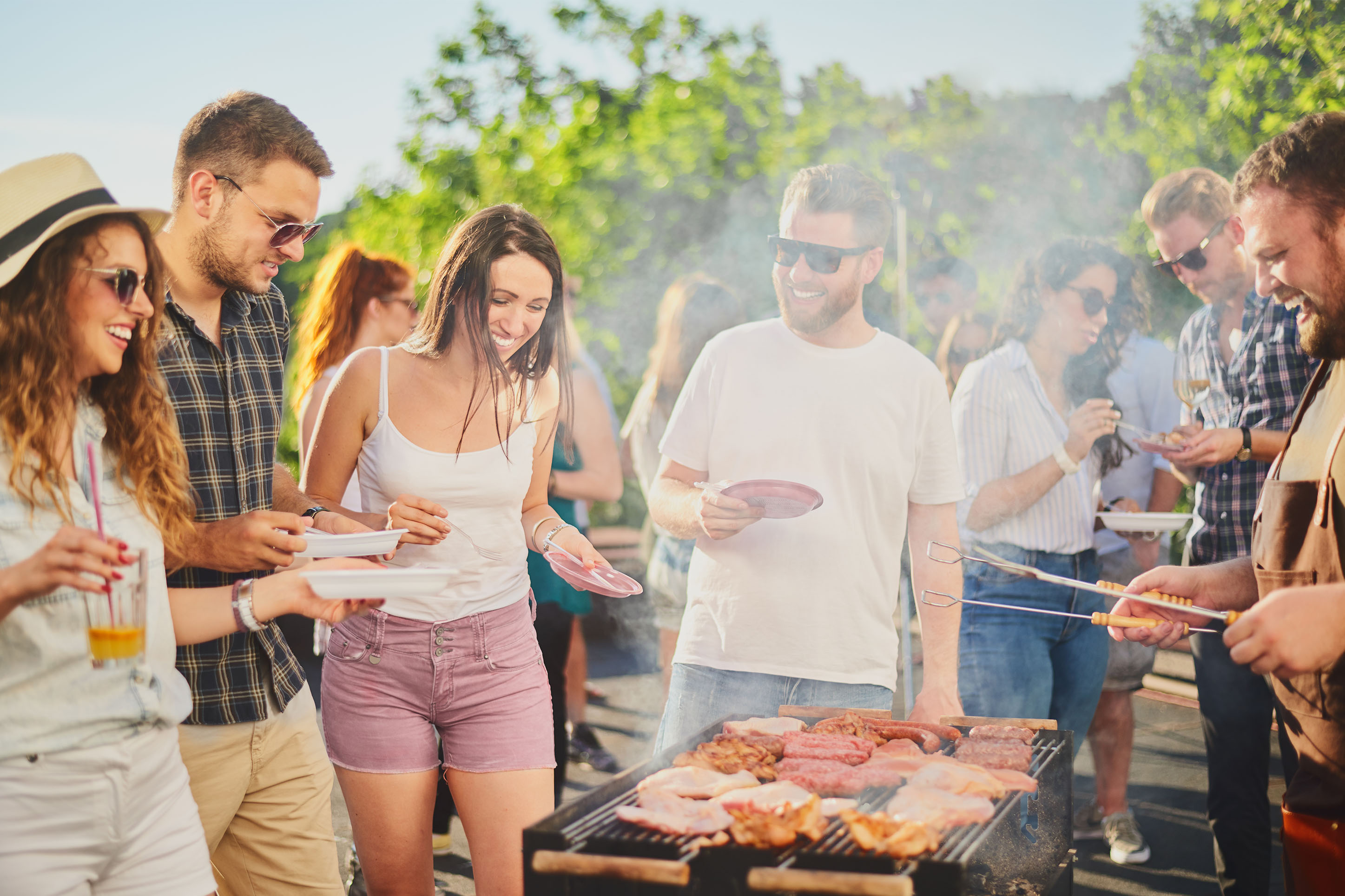 Friends gathered around a grill outdoors in the summertime